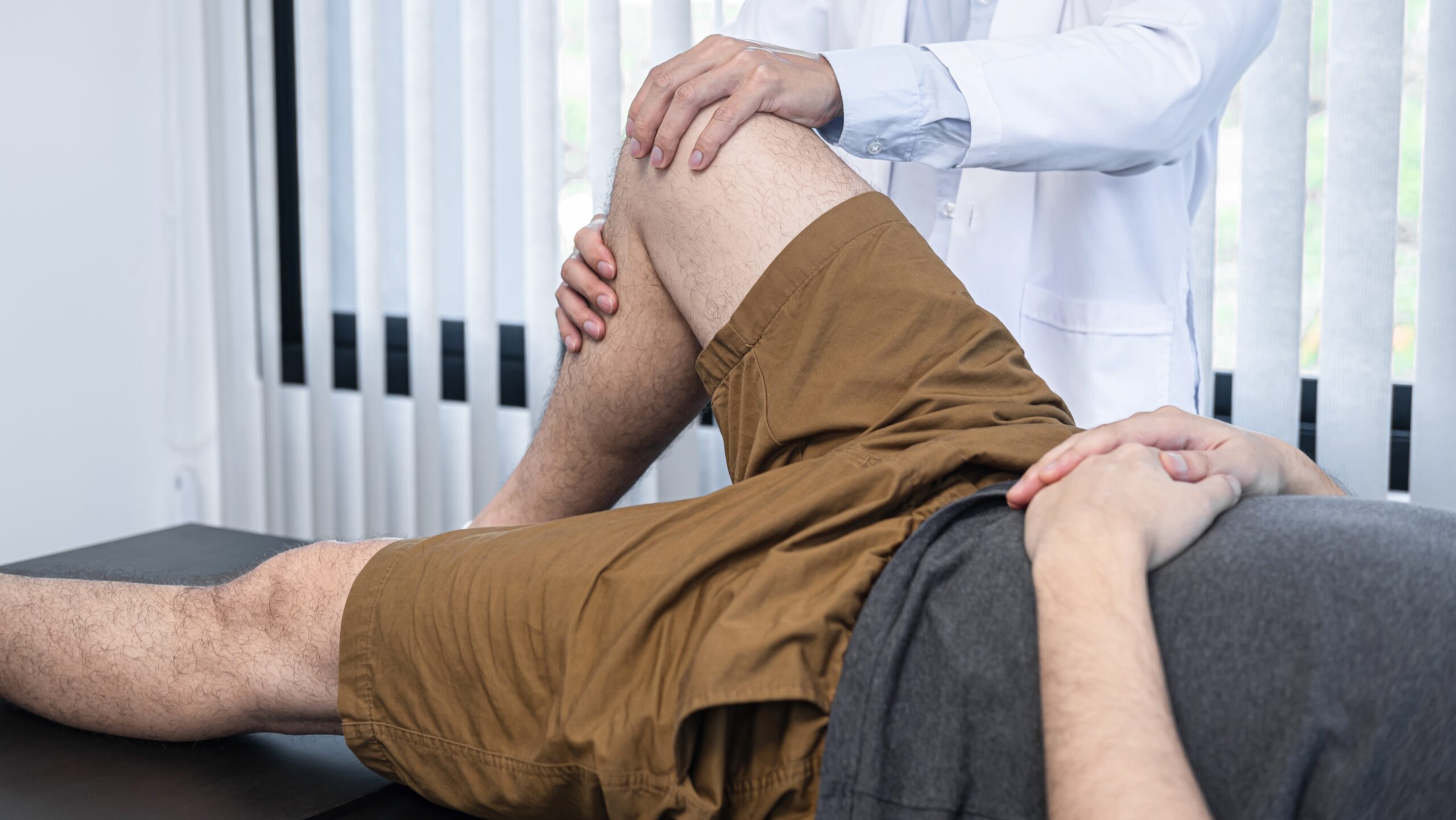 Young asian physiotherapist checking knee joint with injury to g